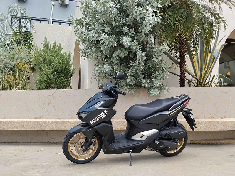 a black honda click 160 scooter hub rental bike parked in front of a wall in the umong area of chiang mai