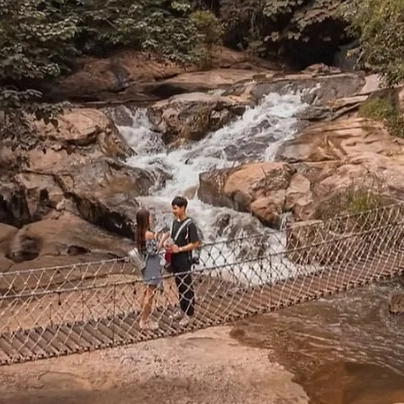 一对情侣在沙孟 River Rock 咖啡馆的桥上休息，享受附近的瀑布