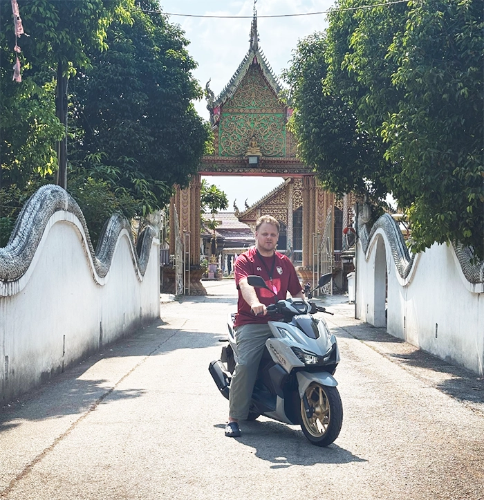 a scooter hub customer riding a honda click 160 in front of a chiang mai temple